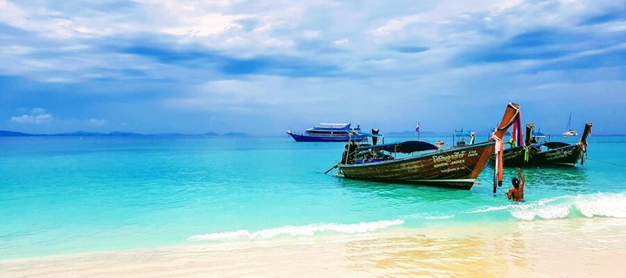 Boats pulled to shore with turquoise colored ocean and dark clouds in the background.